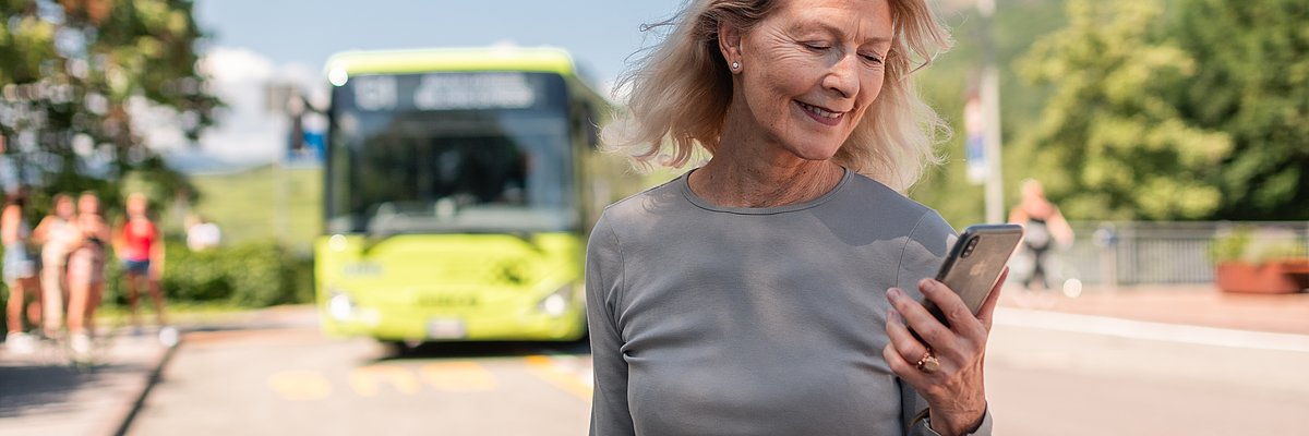 Woman with mobile next to a bus