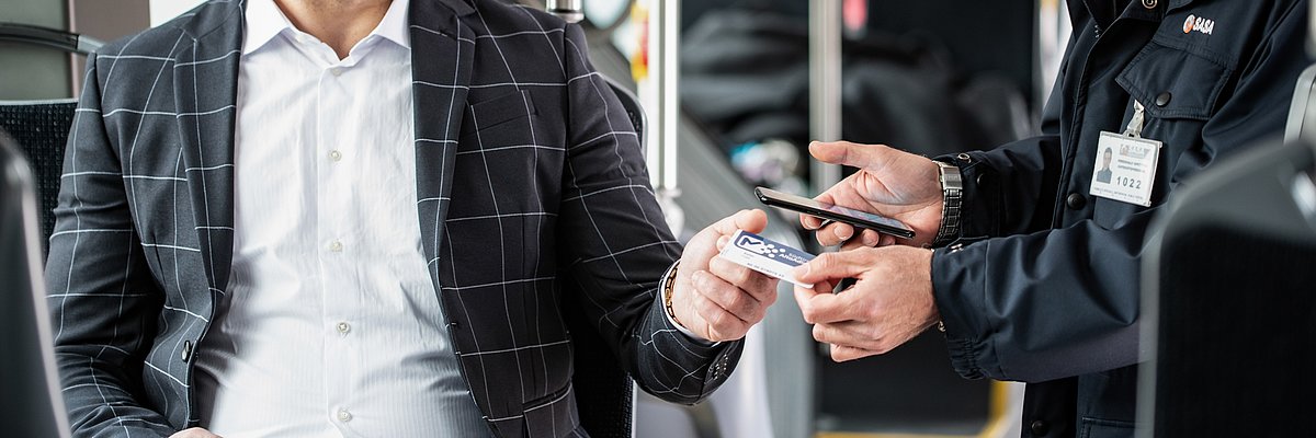 Detail of the hands of a ticket inspector and a passenger, while checking the ticket.