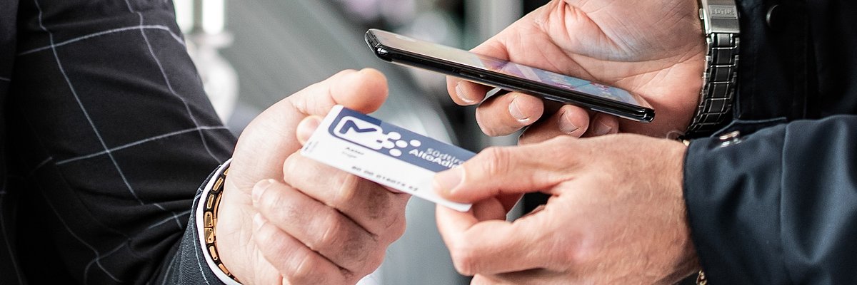 Detail of the hands of a ticket inspector and a passenger, while checking the ticket.