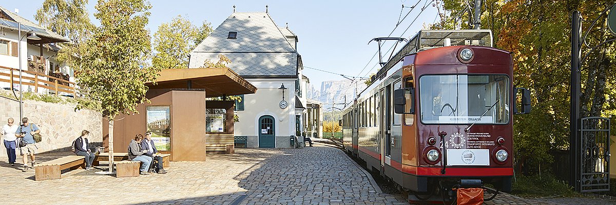Persone in attesa alla fermata di Soprabolzano. Trenino del Renon in partenza.