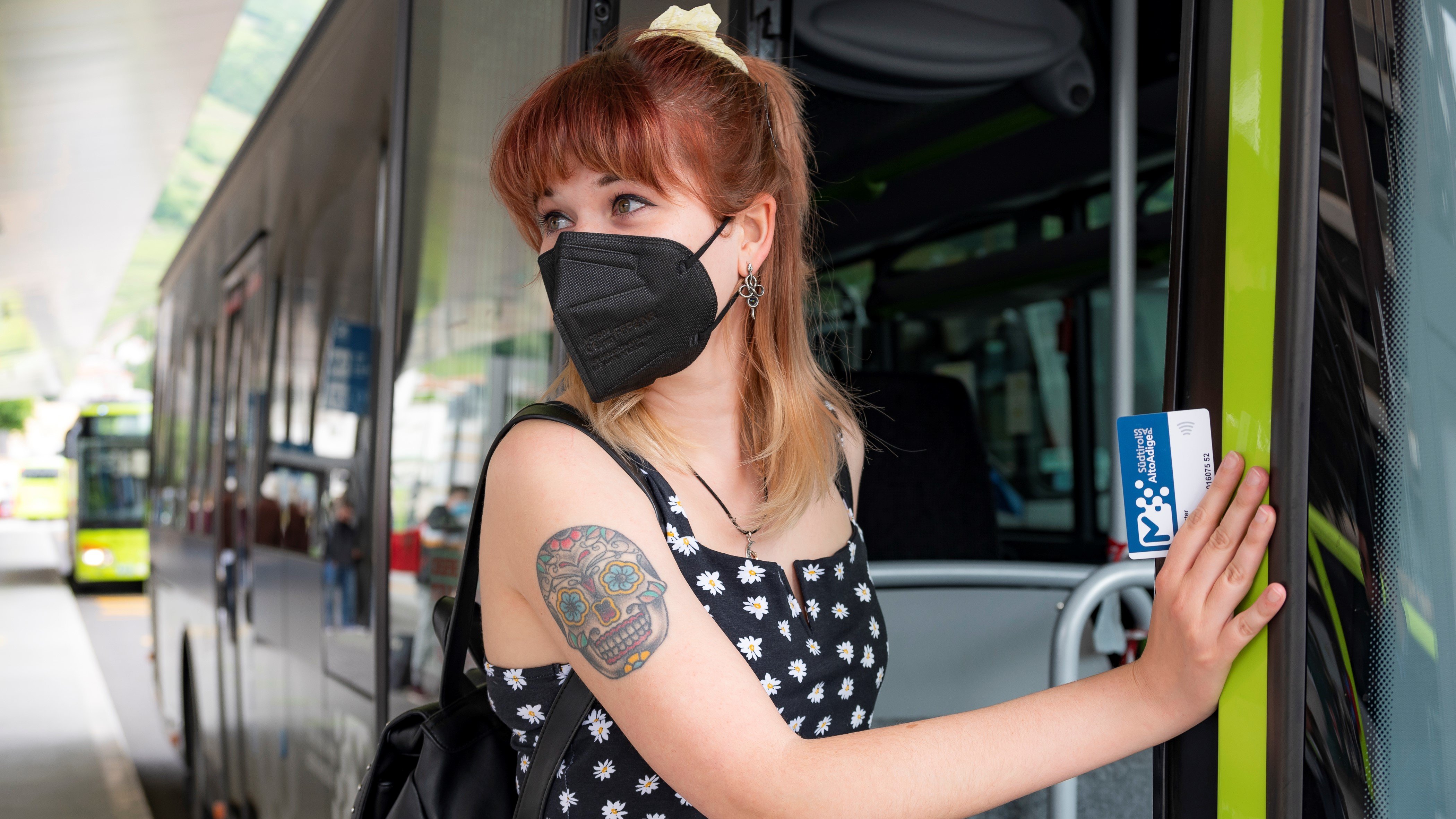 Una ragazza con mascherina FFP2 sta salendo sull'autobus.